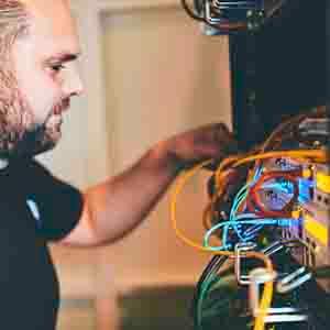 Technician in front of a server rack, looking at cables