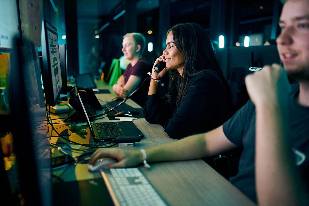 Drei Teammitglieder im Network Operations Center (NOC), eine Person am Telefon